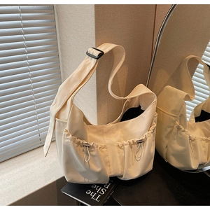 Détail d'un sac dumpling en toile crème avec poches à cordon et bandoulière réglable