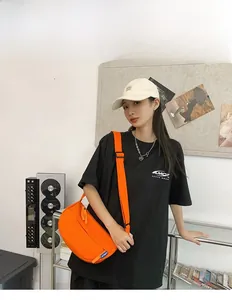 Detail of bright orange canvas crossbody bag with adjustable strap on a model