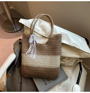 Detail of handmade straw tote bag featuring brown and cream color-blocking and lace charm