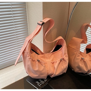 Détail du sac hobo en nylon rose montrant de grandes poches à cordon et bandoulière