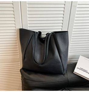 Detail einer schwarzen Tote Bag aus genarbtem Leder mit goldenem Magnetverschluss