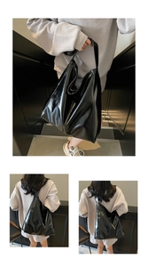 Close-up of a large black glossy tote bag with polished finish and wide shoulder straps