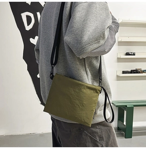 Rear view of a model wearing an olive green waterproof nylon crossbody messenger bag
