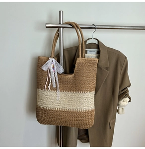 Close-up of woven straw tote bag with brown stripes, lace bow, and colorful beads