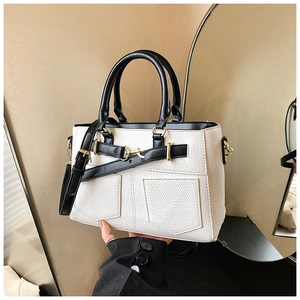 Detail of minimalist cream leather bucket bag with black trim and gold hardware