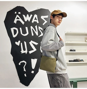 Army green nylon envelope bag styled as a crossbody on a model in an urban setting