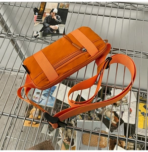 Close-up of vibrant orange nylon sports waist bag on a metallic mesh display