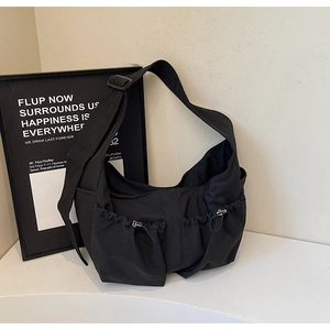 Détail du sac bandoulière en nylon noir avec poches à cordon et large bandoulière réglable