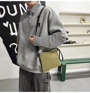 Detailed view of the olive green crossbody envelope bag worn by a model in casual style