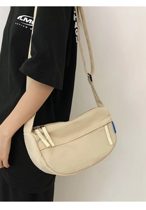 Close-up of beige crescent crossbody bag showing nylon texture and adjustable shoulder strap