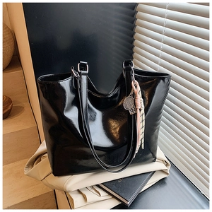 Detail of glossy black PU leather tote with brand embossing and tennis racket charm