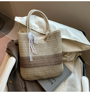 Detail of woven straw tote bag featuring brown stripes and delicate lace tassels