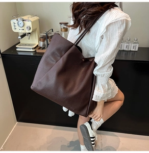 Detail einer dunkelbraunen Tote-Tasche mit Kieselledertextur an der Schulter