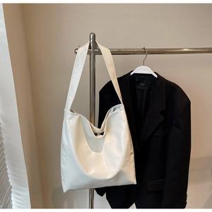 Detail of white glossy leather tote bag showing soft texture on a metal hanger