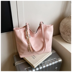 Detailed close-up of pink glossy patent leather tote bag with textured embossed lettering