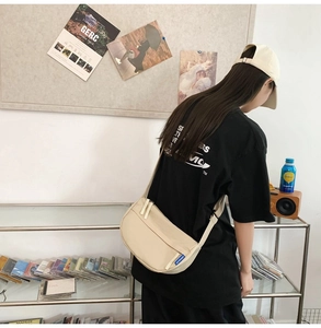 Rear view of a model wearing the beige crescent crossbody bag with adjustable strap