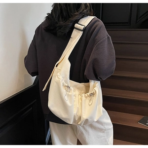 Détail du sac plissé minimaliste en nylon blanc cassé avec bandoulière réglable noire