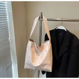 Close-up of a soft cream pink tote bag hanging on a silver metal hanger with a minimal design