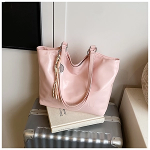 Detailed macro of pink PU leather tote bag with embossed logo and woven fringe charm
