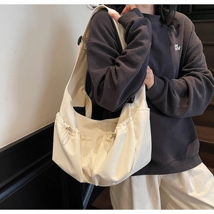 Détail du côté plissé à cordon sur le grand sac bandoulière en nylon crème pour femme