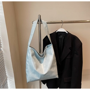Detail view of a light blue Hobo shoulder bag made of soft leather on a stainless steel rack