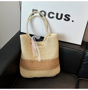 Detail of two-tone woven straw tote bag with white lace ribbon on a black sofa
