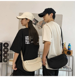 Close-up of minimalist canvas half-moon crossbody bags in beige and black worn by models