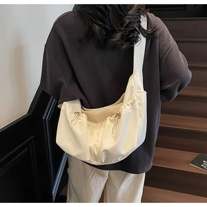 Sac bandoulière en nylon plissé crème, vue latérale portée par un mannequin