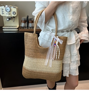 Close-up of a woven straw tote bag with white lace ribbon and colorful bead charms