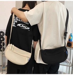 Detail of minimalist crescent crossbody bags in cream and black with nylon texture