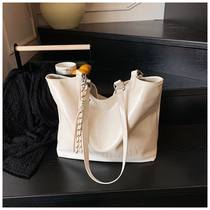 Close-up of off-white large tote bag with glossy patent leather and embossed bottom text