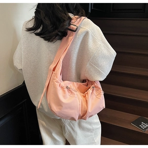 Sac bandoulière plissé en nylon rose sur mannequin montrant le volume et le drapé