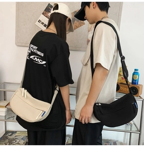 Couples wearing minimalist crescent crossbody bags in cream and black with blue side tags
