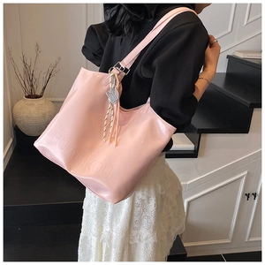 Close-up of pink patent leather tote bag featuring HUANIKOU embossed lettering and tennis charm