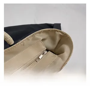 Detail shot of the internal zipper pocket and beige lining of the straw beach tote bag