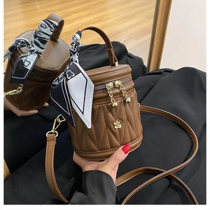 Close-up of brown quilted bucket bag with gold hardware and elegant scarf detail
