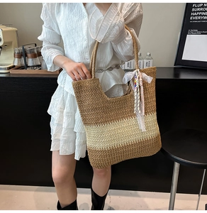 Detail of striped straw tote bag featuring white lace bow and beaded tassel accessory