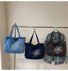 Detail der Spinnennetz- und roten Spinnenstickerei auf gewaschenen Denim-Taschen