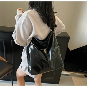Glossy black patent leather tote bag shown on model for size and style reference