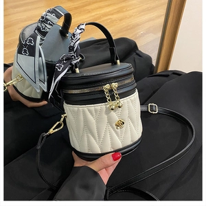 Detail view of quilted black and white bucket bag with silk scarf and gold camellia