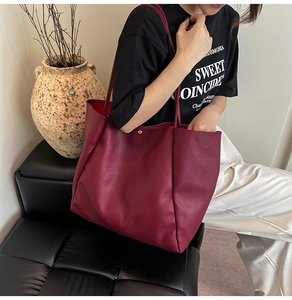 Model trägt eine bordeauxrote Shopper-Tasche aus hochwertigem Kunstleder mit Kieselstruktur
