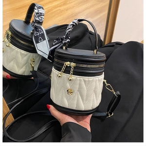 Detailed view of quilted bucket bag with camellia ornament and silk scarf handle
