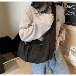 Détail du sac bandoulière en nylon noir plissé avec cordon de serrage latéral