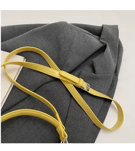 Detail of adjustable bright yellow faux leather shoulder strap with silver metal buckle