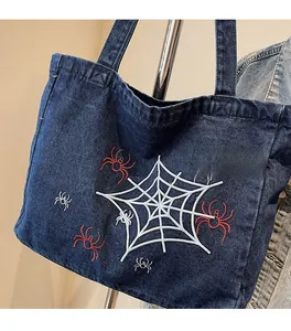 Detail der gotischen Spinnennetz-Stickerei auf einer robusten dunkelblauen Denim-Tasche