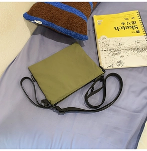 Detail view of olive green nylon envelope crossbody bag with adjustable black strap