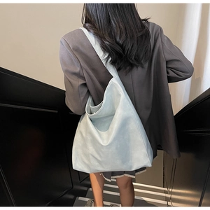 Close-up of minimalist light blue soft leather tote bag worn by a model in suit