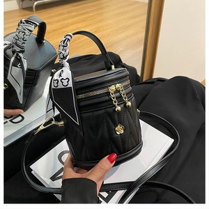 Detail of black quilted bucket bag with gold floral accents and silk scarf handle