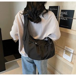 Vue détaillée arrière d'un grand sac bandoulière en nylon noir avec poches à cordon
