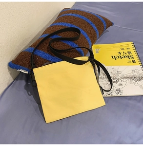 Detail of a bright yellow square nylon messenger bag with an adjustable black shoulder strap